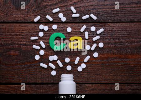 Papiersymbol Ca (Calcium), medizinische Flasche und Pillen auf Holztisch, Draufsicht Stockfoto