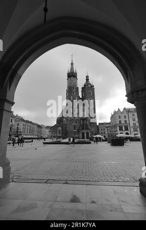 Schwarzweißbild der Basilika St. Marys aus den Bögen der Tuchhalle. Krakau, Polen, Europa. Stockfoto