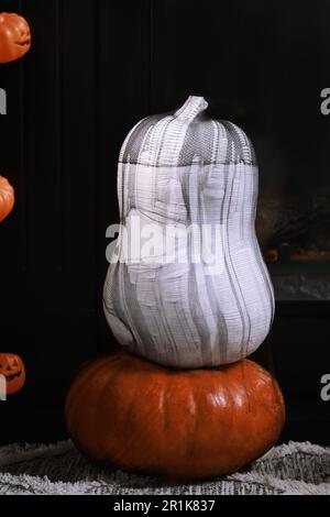 Bunte Kürbisse auf Teppich neben dem Kamin. Halloween-Dekoration Stockfoto