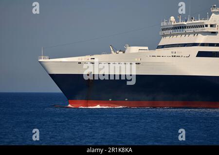 Nahaufnahme des Hecks eines Schiffes, das auf dem Meer segelt. Sie können das Steuerhaus des Kapitäns sehen, den Anker an Bord hängen. Das Schiff ist blau im Hintergrund Stockfoto