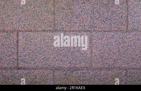 Nahaufnahme einer Wand aus natürlichen roten Granitsteinen, Vorderansicht. Abstrakter texturierter Vollformathintergrund. Speicherplatz kopieren. Stockfoto