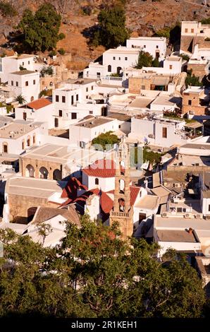 Das griechische Dorf Lindos mit schneeweißen Häusern und engen Gassen. Blick von oben auf die Terrassen von Häusern und Keramikkuppeln von Kirchen Stockfoto