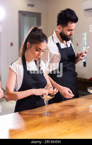 Chefkoch kocht hausgemachtes Tiramisu in Glasgefäßen Kochen in der Küche. Traditionelles ungebackenes italienisches Dessert. Kaffee und Mascarpone-Kuchen Stockfoto