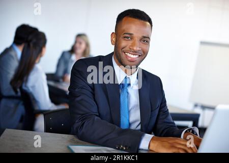 Ein Anführer auf seinem Gebiet. Ein attraktiver junger Geschäftsmann, der im Büro an einem Laptop arbeitet. Stockfoto