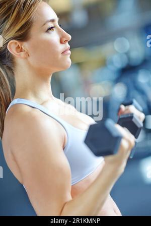 Ich mache große Fortschritte. Eine wunderschöne junge Frau, die im Fitnessstudio trainiert. Stockfoto