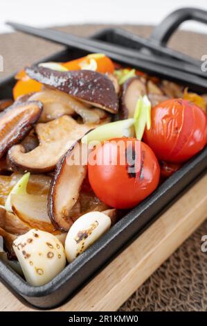 Gebratene Shiitake-Pilze mit Gemüse, Paprika, Zwiebeln und Tomaten sind verzehrfertig. Vegetarisches Gericht mit Shiitake-Pilz Stockfoto