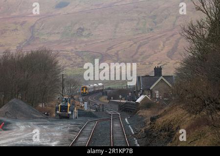 Der Sprinterzug der Northern Rail Klasse 158 fährt vom Bahnhof Ribblehead mit der Settle-Carlisle-Bahn ab, wobei die Frachtgleise im Vordergrund stehen Stockfoto