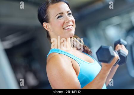 Ich mache große Fortschritte. Eine wunderschöne junge Frau, die im Fitnessstudio trainiert. Stockfoto