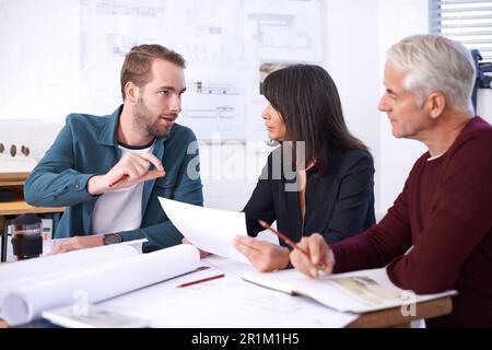 Ideen und Meinungen austauschen. Drei Architekten arbeiten an einem neuen Gebäudeentwurf. Stockfoto