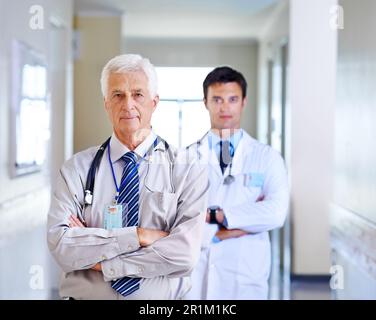 Das Team, dem Sie vertrauen können. Porträt von zwei ernsthaften Ärzten, die in einem Krankenhausgang stehen. Stockfoto