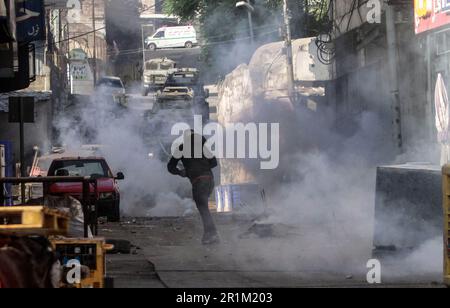 Nablus, Palästina. 14. Mai 2023. Ein palästinensischer Jugendlicher wirft während des Überfalls in der Stadt Nablus Steine auf die Fahrzeuge der israelischen Armee, um einige gesuchte Personen von den israelischen Behörden östlich von Nablus im besetzten Westjordanland zu verhaften. Kredit: SOPA Images Limited/Alamy Live News Stockfoto