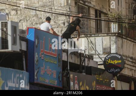 Nablus, Palästina. 14. Mai 2023. Ein palästinensischer Jugendlicher wirft während des Überfalls in der Stadt Nablus Steine auf die Fahrzeuge der israelischen Armee, um einige gesuchte Personen von den israelischen Behörden östlich von Nablus im besetzten Westjordanland zu verhaften. Kredit: SOPA Images Limited/Alamy Live News Stockfoto