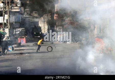 Nablus, Palästina. 14. Mai 2023. Palästinensische Jugendliche fliehen aus Tränengaskanistern, die von den israelischen Streitkräften während des Überfalls in der Stadt Nablus abgefeuert wurden, um einige gesuchte Personen von den israelischen Behörden östlich von Nablus im besetzten Westjordanland zu verhaften. Kredit: SOPA Images Limited/Alamy Live News Stockfoto