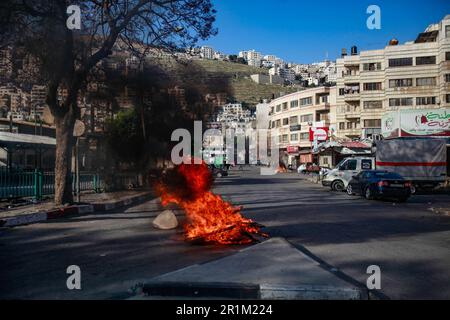 Nablus, Palästina. 14. Mai 2023. Ein Blick auf brennende Reifen, die von palästinensischen Jugendlichen vor israelischen Militärfahrzeugen während des Überfalls in der Stadt Nablus platziert wurden, um einige von den israelischen Behörden östlich von Nablus gesuchte in dem besetzten Westjordanland-Kredit zu verhaften: SOPA Images Limited/Alamy Live News Stockfoto