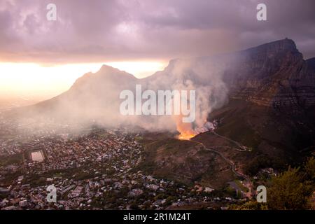 Eine kontrollierte Verbrennung am Fuße des Tafelbergs bei Sonnenaufgang im März 2023, die Aussicht vom Lions Head Mountain, Kapstadt, Südafrika Stockfoto