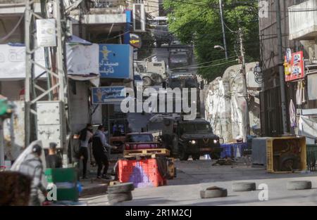 Nablus, Palästina. 14. Mai 2023. Ein palästinensischer Jugendlicher wirft während des Überfalls in der Stadt Nablus Steine auf die Fahrzeuge der israelischen Armee, um einige gesuchte Personen von den israelischen Behörden östlich von Nablus im besetzten Westjordanland zu verhaften. (Foto von Nasser Ishtayeh/SOPA Images/Sipa USA) Guthaben: SIPA USA/Alamy Live News Stockfoto