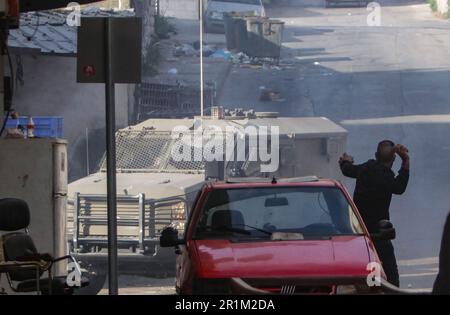 Nablus, Palästina. 14. Mai 2023. Ein palästinensischer Jugendlicher wirft während des Überfalls in der Stadt Nablus Steine auf die Fahrzeuge der israelischen Armee, um einige gesuchte Personen von den israelischen Behörden östlich von Nablus im besetzten Westjordanland zu verhaften. (Foto von Nasser Ishtayeh/SOPA Images/Sipa USA) Guthaben: SIPA USA/Alamy Live News Stockfoto