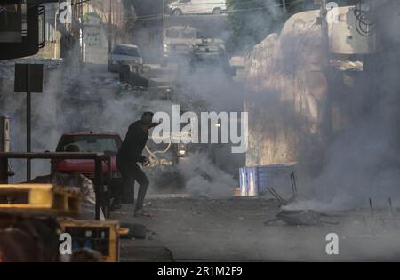 Nablus, Palästina. 14. Mai 2023. Ein palästinensischer Jugendlicher wirft während des Überfalls in der Stadt Nablus Steine auf die Fahrzeuge der israelischen Armee, um einige gesuchte Personen von den israelischen Behörden östlich von Nablus im besetzten Westjordanland zu verhaften. (Foto von Nasser Ishtayeh/SOPA Images/Sipa USA) Guthaben: SIPA USA/Alamy Live News Stockfoto