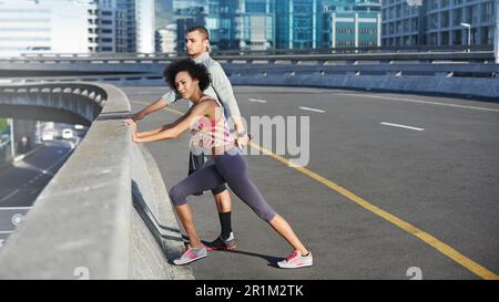 Diese Dehnübungen werden langfristig helfen. Zwei Freunde machen sich bereit für einen gemeinsamen Joggingausflug durch die Straßen der Stadt. Stockfoto