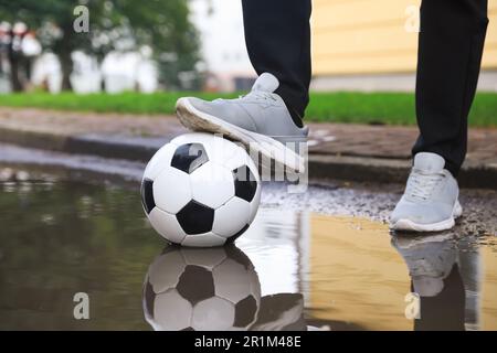 Mann mit Fußball in der Nähe der Pfütze, Nahaufnahme Stockfoto