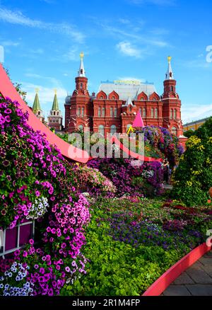 Blumenfestival im Zentrum von Moskau im Sommer, Russland. Historisches Museum im Hintergrund, altes Moskauer Wahrzeichen. Wunderschöne Blumendekorationen in Stockfoto