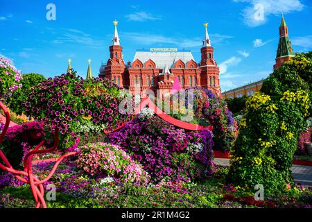 Blumenfestival im Zentrum von Moskau im Sommer, Russland. Historisches Museum im Hintergrund, altes Moskauer Wahrzeichen. Wunderschöne Blumendekorationen in Stockfoto