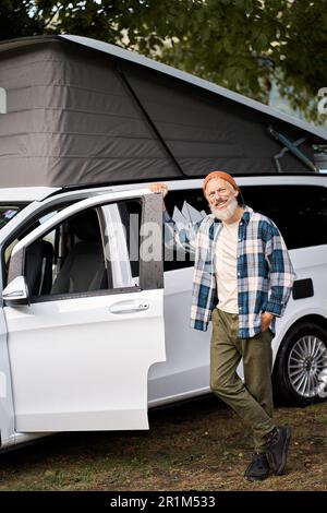 Glücklicher älterer Reisender, der mit Wohnmobil steht, Wohnwagenvermietung. Stockfoto