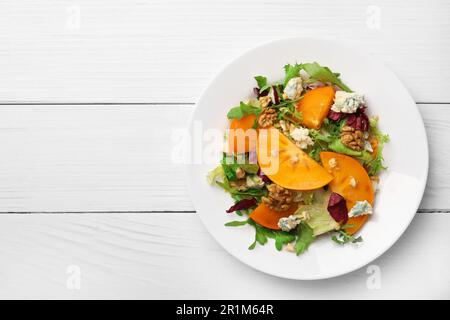 Köstlicher Persimonsalat mit Rucola und Käse auf einem weißen Holztisch, Blick von oben. Platz für Text Stockfoto