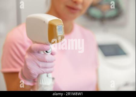 Nahaufnahme eines Lasergeräts in weiblichen Händen zur Entfernung unerwünschter Körperhaare in einem Schönheitssalon Stockfoto