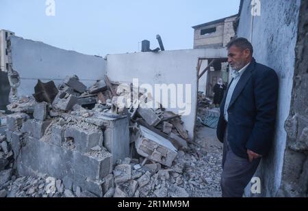 Ein palästinensischer Mann steht vor seinem beschädigten Haus in der Nähe der Ruinen von Banats Familienhaus, das bei einem israelischen Luftangriff zerstört wurde, in Jabaliya im nördlichen Gazastreifen. Der Luftangriff ließ 42 Mitglieder der erweiterten Familie obdachlos. Außerdem blieben vier Kinder mit besonderen Bedürfnissen ohne ihre Rollstühle, Krücken und medizinische Ausrüstung, die sie zum Umherziehen benötigten. Israel sagt, das Gebäude wurde von der militanten Gruppe des Islamischen Dschihad als Kommandozentrale genutzt. Beide Seiten erreichten am Samstag einen Waffenstillstand, um fünf Tage des Kampfes zu beenden. Stockfoto