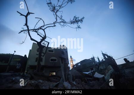 Ein palästinensischer Mann telefoniert in der Nähe der Ruinen von Banats Familienhaus, das bei einem israelischen Luftangriff zerstört wurde, in Jabaliya, nördlicher Gazastreifen, Sonntag, 14. Mai, 2023. Der Luftangriff ließ 42 Mitglieder der erweiterten Familie obdachlos. Außerdem blieben vier Kinder mit besonderen Bedürfnissen ohne ihre Rollstühle, Krücken und medizinische Ausrüstung, die sie zum Umherziehen benötigten. Israel sagt, das Gebäude wurde von der militanten Gruppe des Islamischen Dschihad als Kommandozentrale genutzt. Beide Seiten erreichten am Samstag einen Waffenstillstand, um fünf Tage des Kampfes zu beenden. Stockfoto