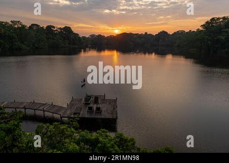 Sonnenaufgang im Amazonas-Regenwald und einheimischer kichwa-Mann im Kanu am Napo River, Yasuni-Nationalpark, Ecuador. Stockfoto