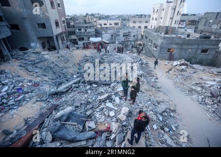 Palästinenser versammeln sich in der Nähe der Ruinen von Banats Familienhaus, das bei einem israelischen Luftangriff zerstört wurde, in Jabaliya, im nördlichen Gazastreifen. Der Luftangriff ließ 42 Mitglieder der erweiterten Familie obdachlos. Außerdem blieben vier Kinder mit besonderen Bedürfnissen ohne ihre Rollstühle, Krücken und medizinische Ausrüstung, die sie zum Umherziehen benötigten. Israel sagt, das Gebäude wurde von der militanten Gruppe des Islamischen Dschihad als Kommandozentrale genutzt. Beide Seiten erreichten am Samstag einen Waffenstillstand, um fünf Tage des Kampfes zu beenden. (Foto: Ahmed Zakot/SOPA Images/Sipa USA) Stockfoto