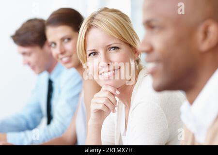 Sie ist bereit, einige brillante Ideen zu liefern. Eine ziemlich reife Geschäftsfrau, die bei einem Meeting mit Kollegen sitzt. Stockfoto