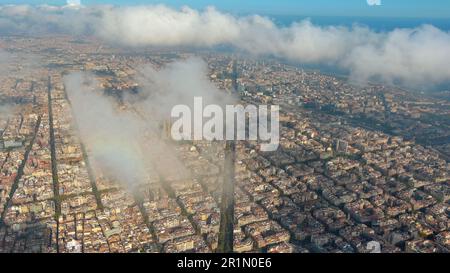 Hubschrauber über die Luftdrohne Barcelona City über den Wolken und Nebel, Basilika Sagrada Familia und das berühmte städtische Netz von Eixample. Katalonien, Spanien Stockfoto