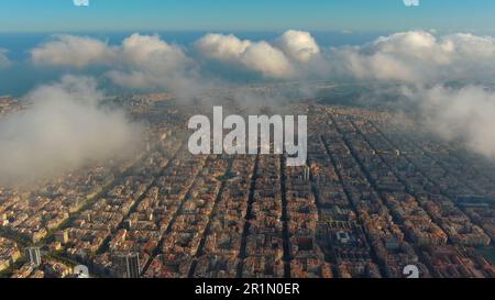 Hubschrauber über die Luftdrohne Barcelona City über den Wolken und Nebel, Basilika Sagrada Familia und das berühmte städtische Netz von Eixample. Katalonien, Spanien Stockfoto