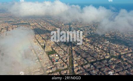 Hubschrauber über die Luftdrohne Barcelona City über den Wolken und Nebel, Basilika Sagrada Familia und das berühmte städtische Netz von Eixample. Katalonien, Spanien Stockfoto