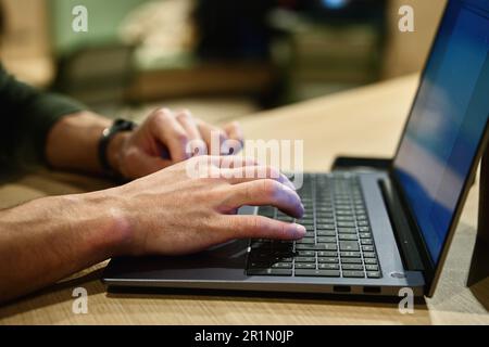 Männliche Hände, die auf der Laptop-Tastatur tippen, Nahaufnahme. Mann, der im Büro ein Notebook benutzt. Online-Arbeit Stockfoto