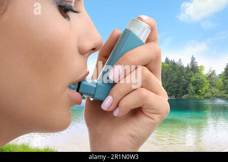 Frau, die Asthmainhalator in der Nähe des Sees benutzt, Nahaufnahme. Erste Notfallhilfe bei Freizeitaktivitäten im Freien Stockfoto