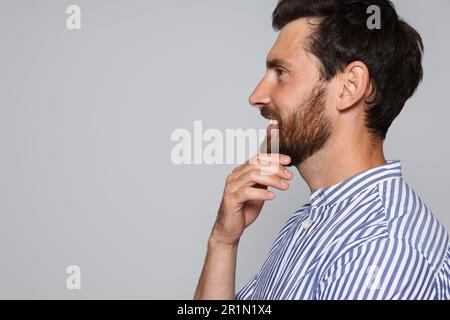 Profilporträt eines lächelnden bärtigen Mannes auf grauem Hintergrund. Platz für Text Stockfoto