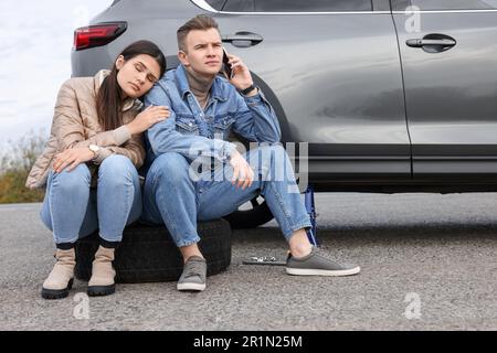 Ein junger Mann ruft beim Autoservice an. Reifenpanne Stockfoto