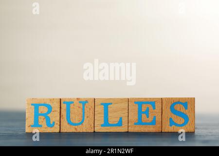 Wortregeln aus Würfeln mit Buchstaben auf hellblauem Holztisch Stockfoto