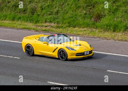 2014 American Chevrolet GMC Corvette, Logo mit gekreuzten Flaggen, Yellow Petrol 6200 ccm, zweitürige, zweisitzige Luxussportwagen; Fahrt auf der Autobahn M61 UK Stockfoto