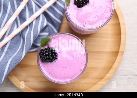 Köstlicher BrombeerSmoothie in Gläsern auf weißem Holztisch, Draufsicht Stockfoto