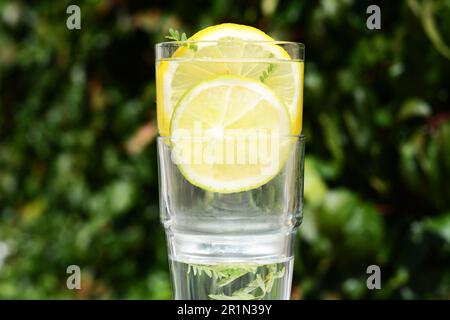 Köstliche erfrischende Limonade vor grünem, verschwommenem Hintergrund, Nahaufnahme Stockfoto