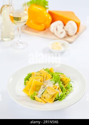 Ravioli mit grünem Salat und weißer Sauce. Stockfoto