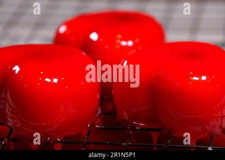 Mousse Cake Red Prepare Pastry Chef gießt flüssigen Beerenrot Sirup auf Mousse Cakes auf einem Kühlgestell aus Draht. Hochwertige 4K-Aufnahmen Stockfoto