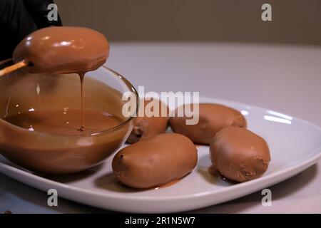 Schokoladenkuchen mit Kakaopulver, Kartoffelkuchen mit Schokoladenstückchen und Kaffee mit Kakao bestreuen. Kochdessert in Milchschokolade getaucht Stockfoto