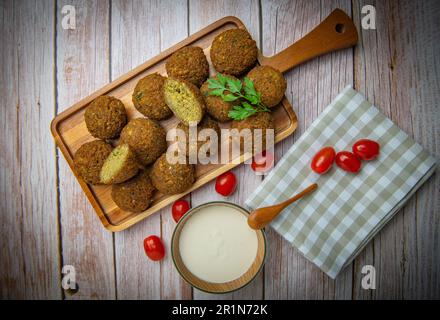 Falafel-Kugeln auf einem Holzbrett und Tahini-Sauce Stockfoto