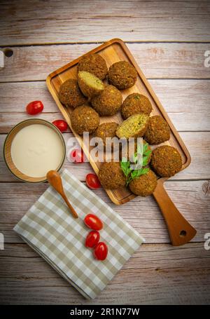 Falafel-Kugeln auf einem Holzbrett und Tahini-Sauce Stockfoto